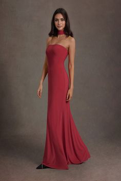 a woman in a long red dress posing for the camera with her hands on her hips