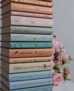 a stack of books sitting on top of a table next to a bouquet of flowers