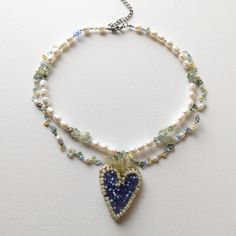 This pearl necklace for women is handcrafted in light green, blue, beige colors.Large Heart pendant handembroidered with beads, gold velvet inside out.Necklace length ~15 inches (38 cm) + 3" (7 cm) extra chain. If you want another length massage to me freely. Heart size: Height 4,5 cm, Width 3,5 cm The necklace made in fairycore style. The product uses highquality steel metal that will not lose color even when in contact with water and creams.Materials:pearl category AAgreen agatmixed seed beads Elegant Heart-shaped Beaded Necklaces, Blue Heart Beads Pendant Necklace, Pearl Necklace With Heart, Elegant Heart-shaped Beaded Necklace With Pearl Charm, Beaded Flower-shaped Pearl Necklace, Heart Pearl Necklace, Elegant Flower-shaped Necklace With Colorful Beads, Necklace With Heart, Color Jewelry