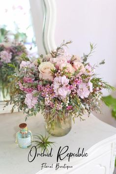 a vase filled with pink flowers sitting on top of a white table next to a mirror