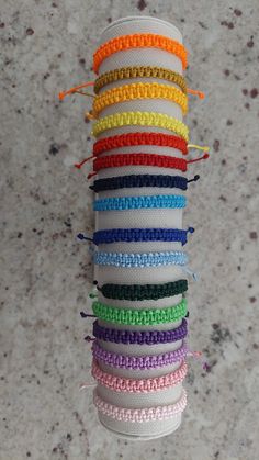 a stack of multicolored bracelets hanging from a hook on a marble surface