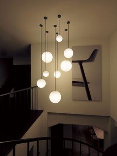 a modern chandelier hanging from the ceiling in a room with white walls and black railing