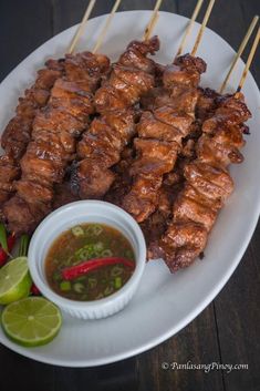 several skewers of meat on a plate with dipping sauce