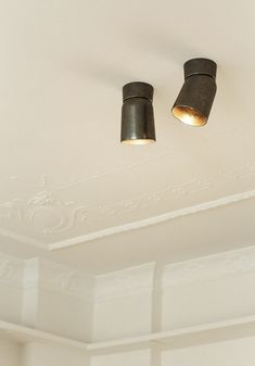 two lights are hanging from the ceiling in a room that has white walls and ceilings