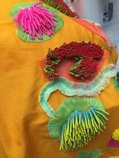 the back of a yellow shirt with flowers and leaves embroidered on it's sides