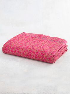 a pink flowered blanket folded on top of a white surface