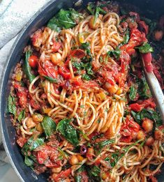 a skillet filled with pasta, spinach and chickpeas in tomato sauce