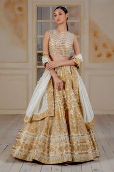 Ivory taffeta 20 kali lehenga with gold applique and crystal highlights Comes with blouse enhanced with chandelier crystals- striped work and chanderi dupatta.
Components:3
Embroidered
Neckline:Round
Sleeve Length:Sleeveless
Fabric:Blouse: Net; Lehenga: Taffeta; Dupatta: Chanderi
Color:Gold, White
Striped pattern
Crystal tassels
Closure: Blouse: Back zip - Aza Fashions Kali Lehenga, Lehenga Designs Latest, Gold Shades, Mirror Work Lehenga, Bridal Sari, Chanderi Dupatta, Gold Applique, Chandelier Crystals, Indian Bride Outfits