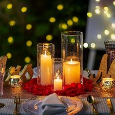 a table topped with candles and plates covered in red roses