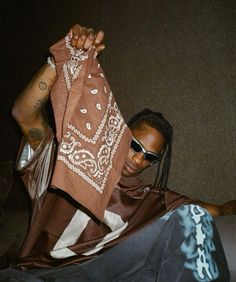 a man sitting on the ground holding up a scarf