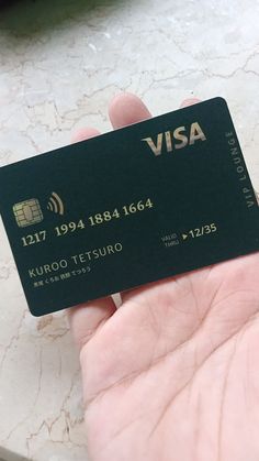 a person holding up a visa card in their left hand, on a marble countertop