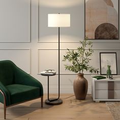 a green chair sitting next to a table with a lamp on it and a plant in a vase