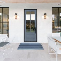 the front door of a house with white chairs and tables on the outside patio area