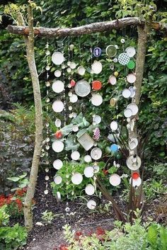 a garden area with various items hanging from the tree and plants growing in the background