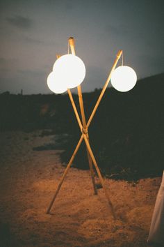 two light poles are standing in the sand at night, one is turned on and the other is off