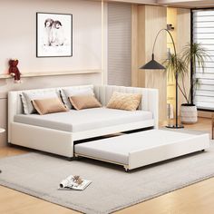 a living room with a white couch, ottoman and coffee table on the floor in front of it