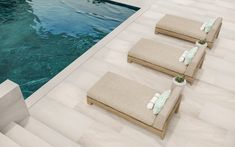 three chaise lounges next to a swimming pool with steps leading up to it