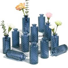 there are many blue vases with flowers in them