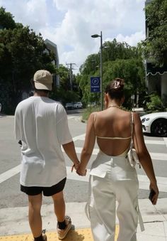 a man and woman walking down the street holding hands