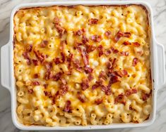 macaroni and cheese with bacon in a white casserole dish on a marble surface