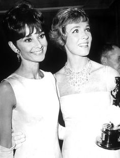 two women standing next to each other holding an oscar award in front of their faces