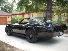 a black sports car parked in front of a house