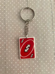 a red and white square shaped keychain with an arrow on it's side