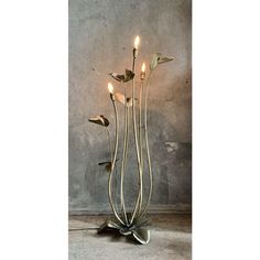 a metal sculpture with three candles on it's sides and leaves in the middle