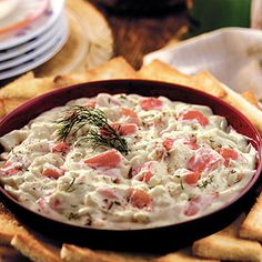 a red bowl filled with dip surrounded by crackers