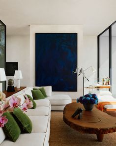 a living room filled with furniture and a large painting on the wall above it's coffee table