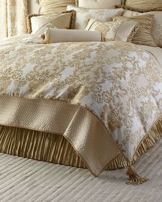 the bed is made up with gold and white comforters, pillows, and blankets