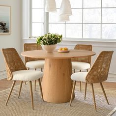 a dining room table with four chairs around it and a bowl of fruit on the table