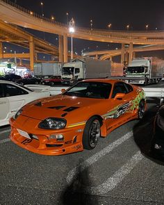 an orange sports car is parked in the parking lot next to other cars and trucks