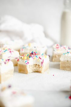 several pieces of cake with sprinkles and a bottle of milk in the background