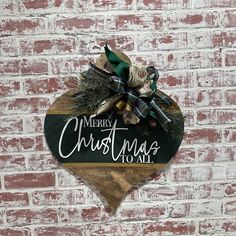 a wooden heart hanging on the side of a brick wall that says merry christmas to all