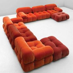 an orange and red couch sitting on top of a white table next to each other