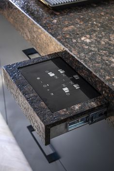 an electronic device sitting on top of a granite counter next to a laptop computer monitor