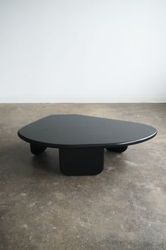 a black table sitting on top of a cement floor next to a white wall in an empty room