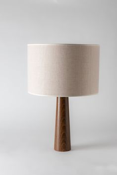 a wooden table lamp with a white shade on it's base and a beige linen lampshade