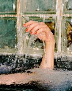 a woman's hand splashing water from a faucet