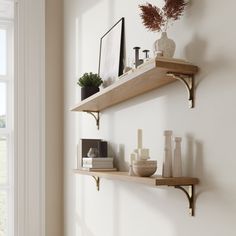 two wooden shelves with vases, candles and other items on them in front of a window