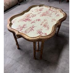 an ornately decorated table with pink and white flowers on the top, sitting in a room