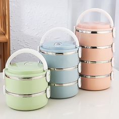 three different colored containers sitting next to each other on a white counter top with a wooden chair in the background