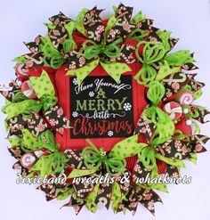 a christmas wreath with the words merry and green bows on it's front door