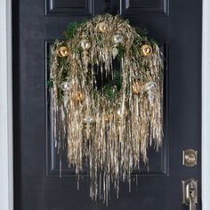 a wreath hanging on the front door of a house decorated with gold and silver ornaments