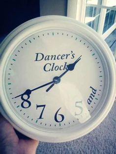 a white clock with the words dancer's clock on it in front of a window