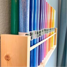 a row of colored papers sitting on top of a wooden shelf