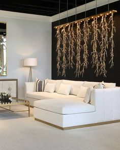 a living room filled with white furniture and lots of plants hanging from the ceiling above