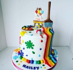 a birthday cake decorated with an artist's palette, paintbrush and rainbows