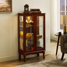 a wooden cabinet with glass doors and shelves in a living room next to a chair